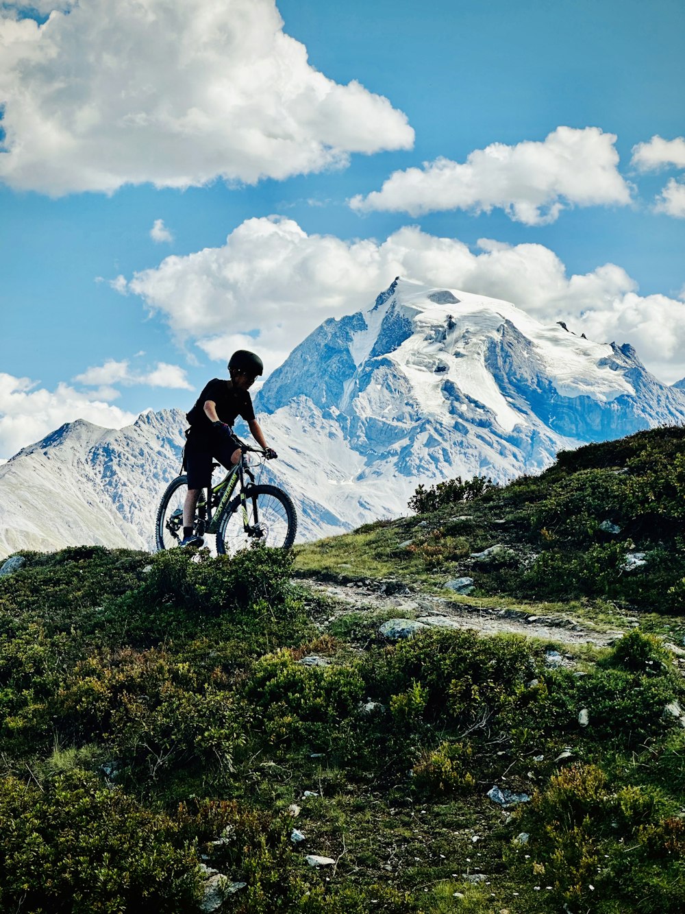 a man riding a bike on top of a lush green hillside