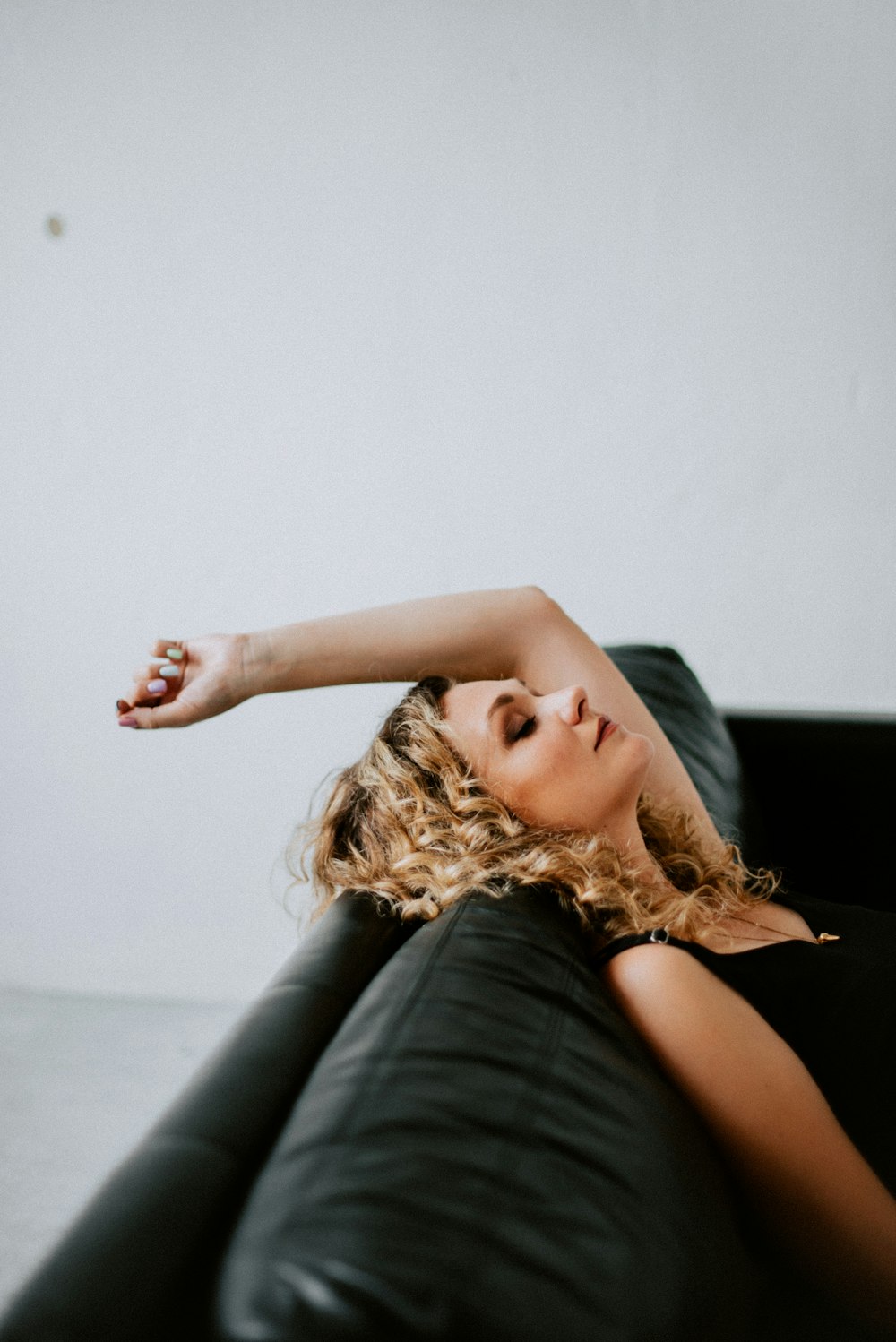 a woman laying on top of a black couch