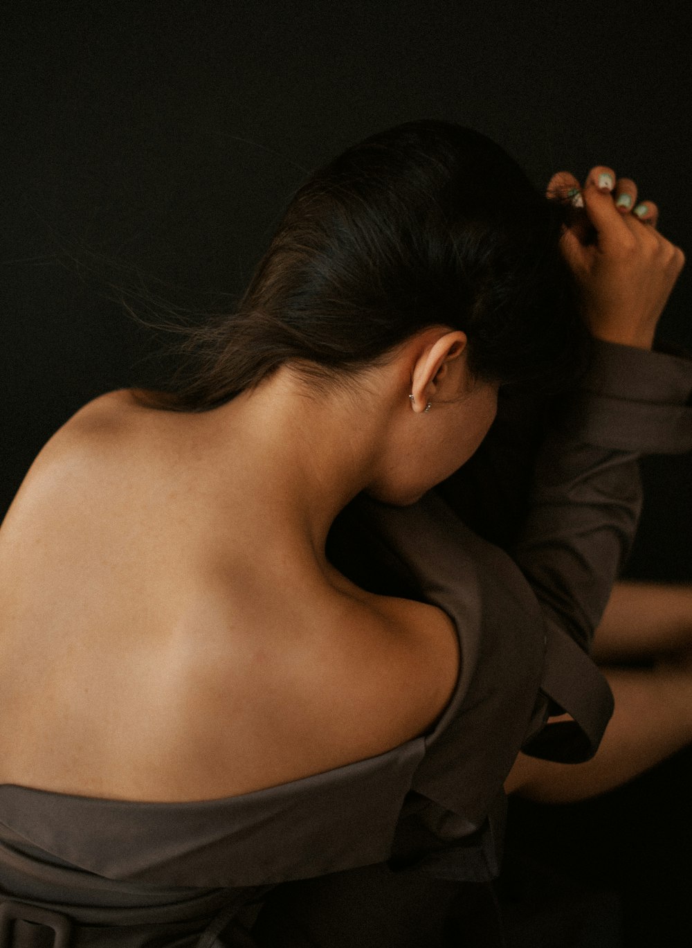 a woman in a brown dress holding her hair back