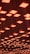 A ceiling installation featuring numerous square light fixtures, each emitting a warm, orange glow. The lights are arranged in a grid pattern and are suspended at varying heights, creating a visually dynamic effect.