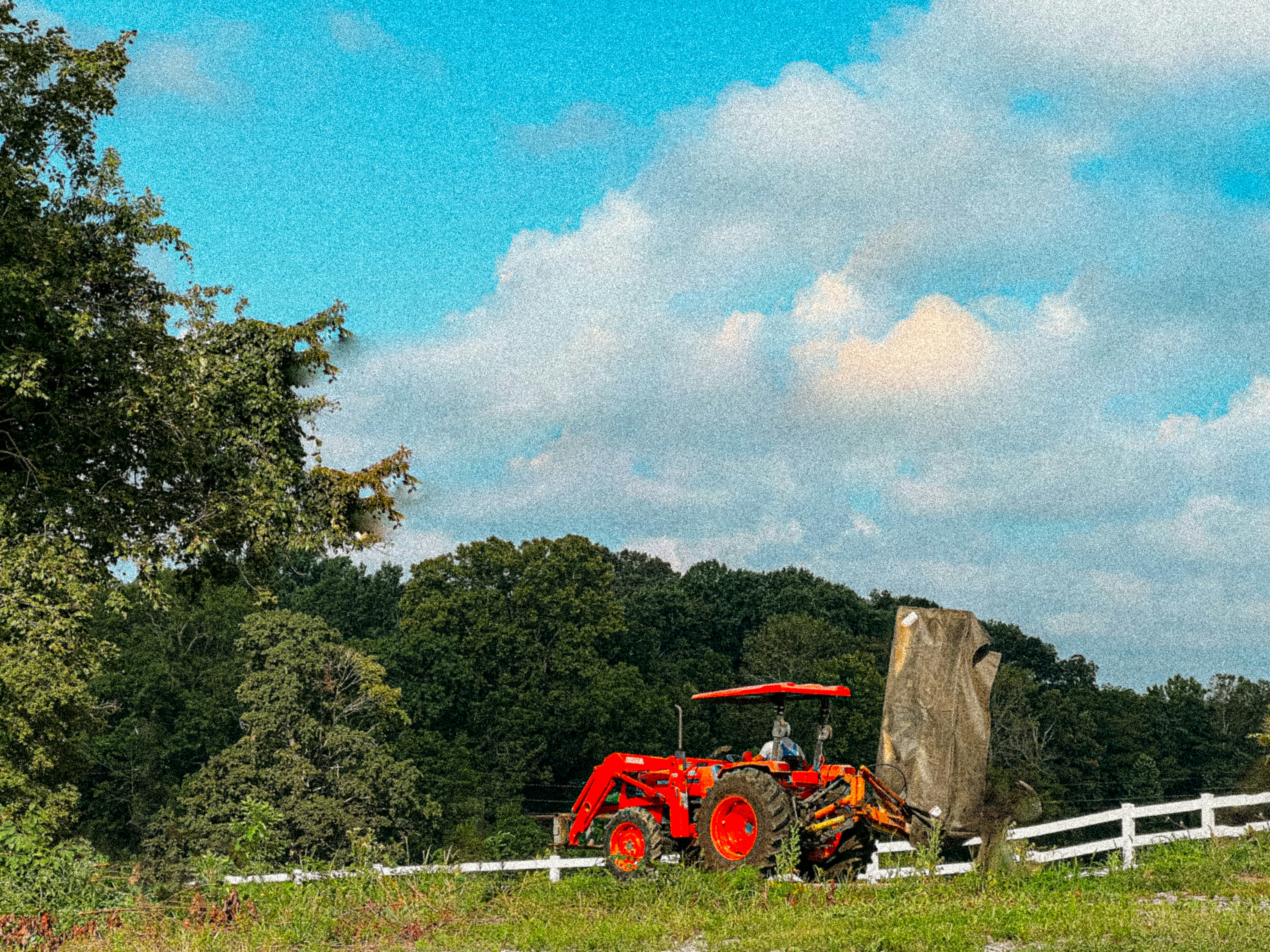 a tractor is parked in a field next to a fence
