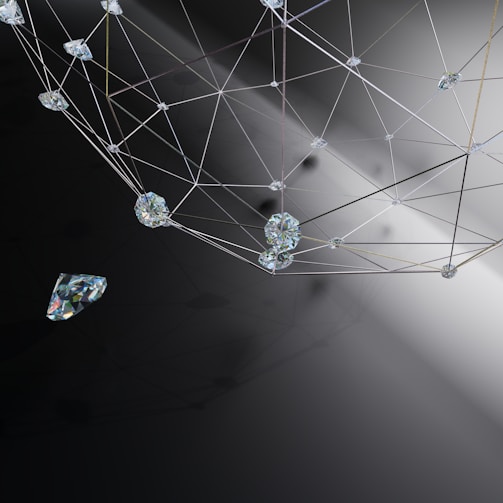 A geometric arrangement of interconnected lines and transparent gemstones or crystals is set against a gradient background. The structure appears to be a network or web, with facets of the gems catching and reflecting light.