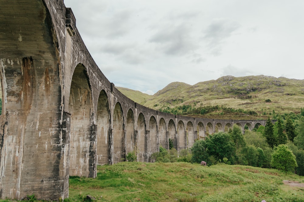 a large stone bridge over a lush green hillside