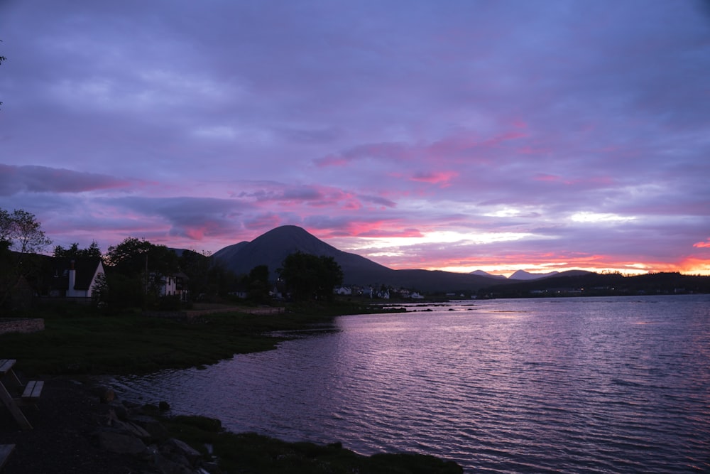 a sunset over a lake with a mountain in the background
