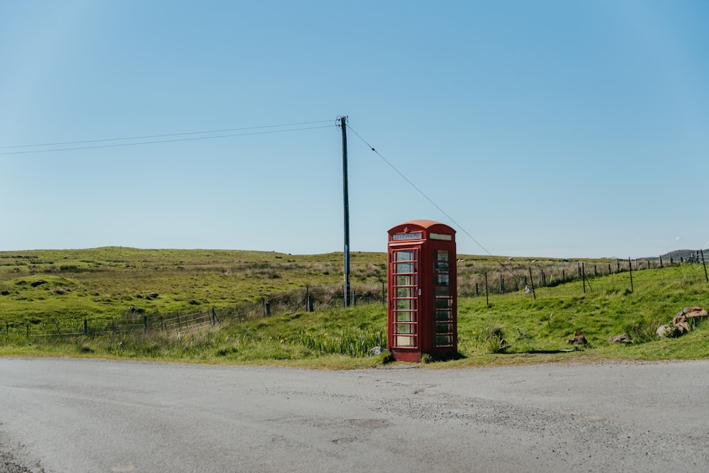 Una cabina telefonica rossa seduta sul ciglio di una strada