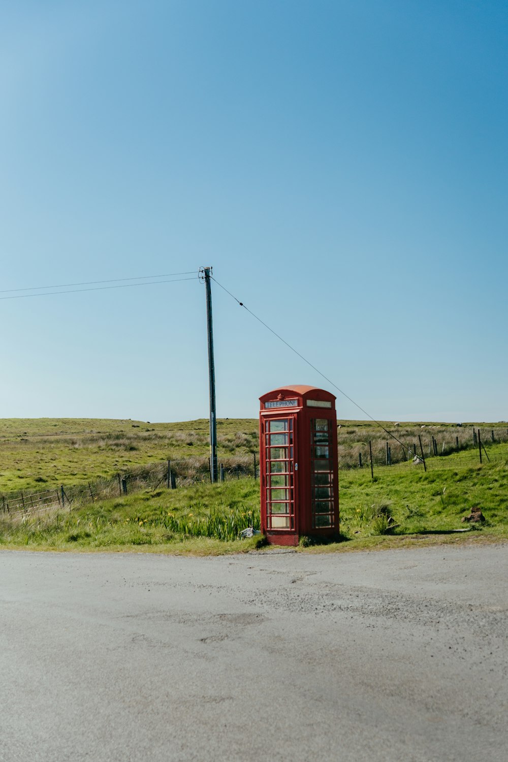 Una cabina telefonica rossa seduta sul ciglio di una strada