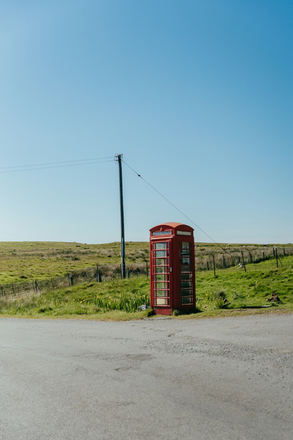 a red telephone booth sitting on the side of a road