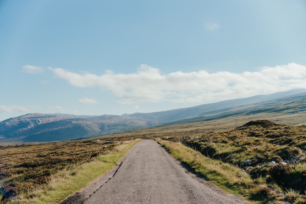 an empty road in the middle of a mountain range