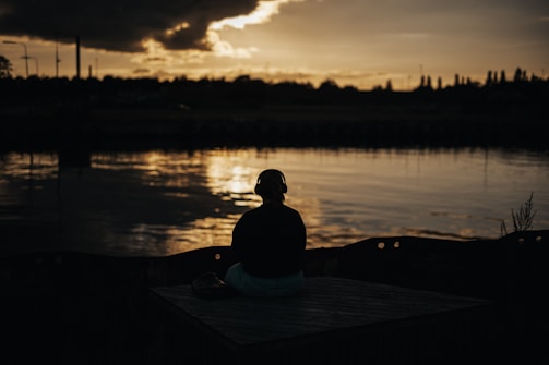A quiet moment of reflection with a person journaling outdoors at sunset.