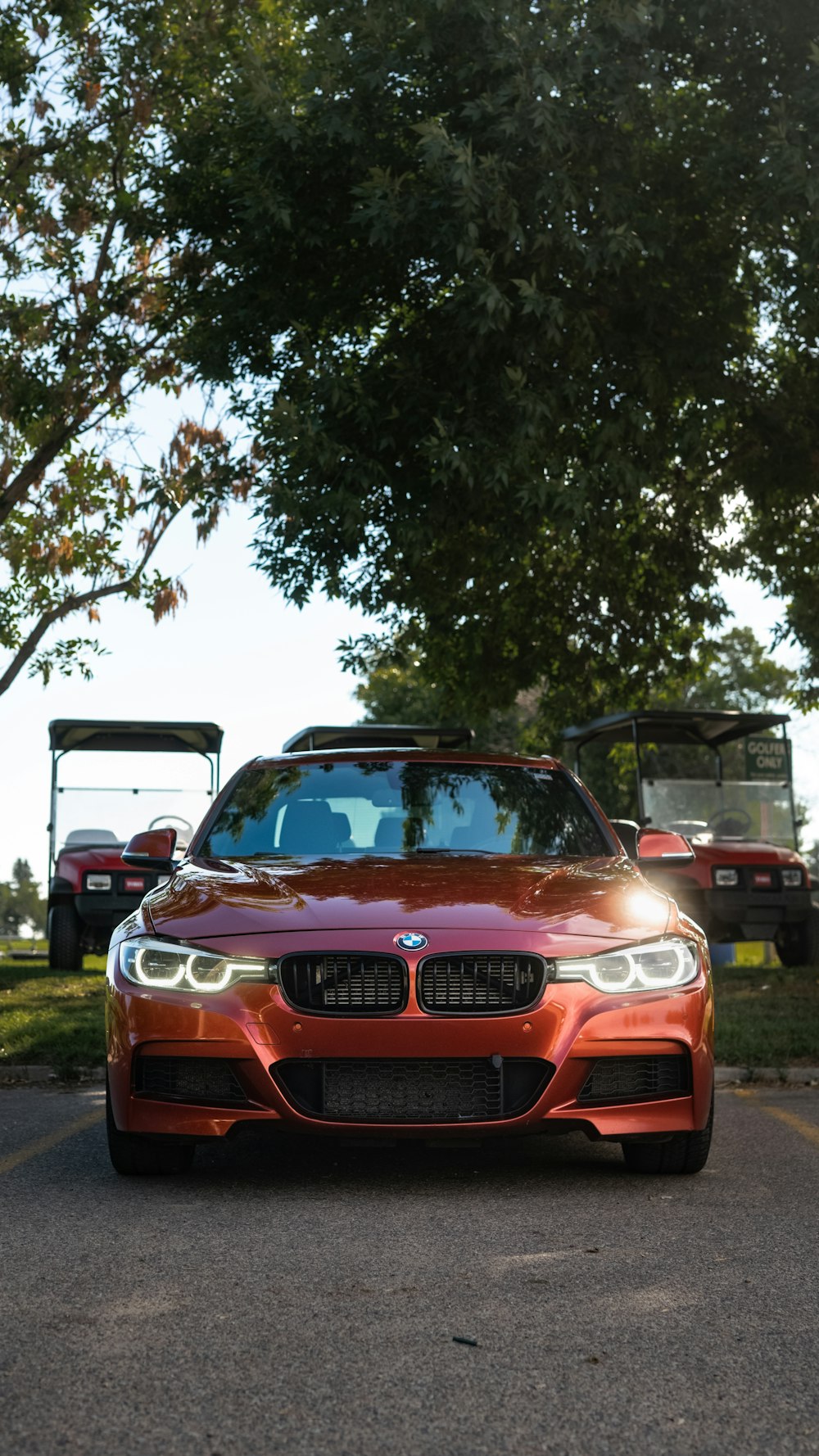 a red car parked in a parking lot next to a golf cart