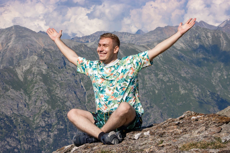 UK sugar daddy on top of a mountain with arms wide open, feeling free