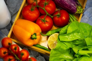 Vibrant assortment of fresh vegetables such as carrots, tomatoes, and spinach displayed on a wooden crate with morning sunlight.