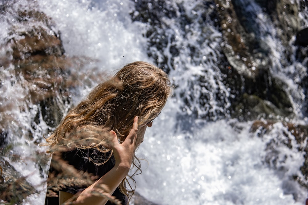 Una mujer parada frente a una cascada