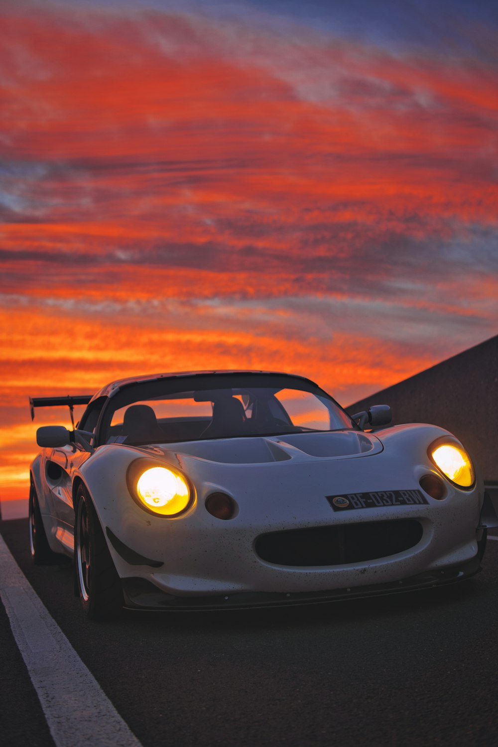 a white sports car driving down a road at sunset