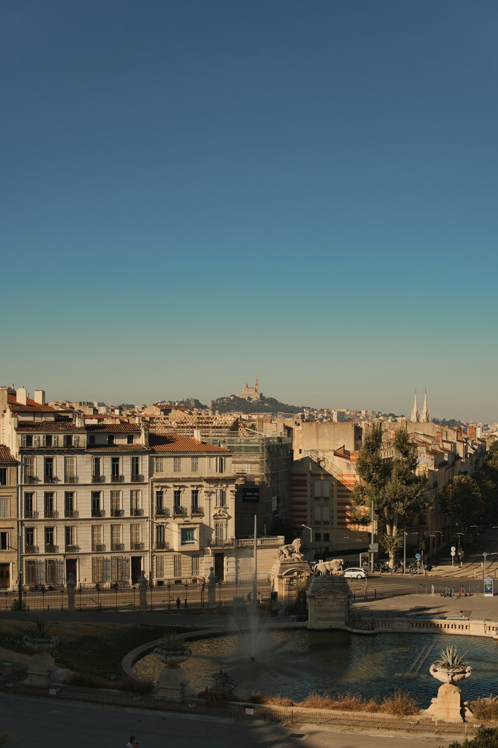 a view of a city with a fountain in the foreground