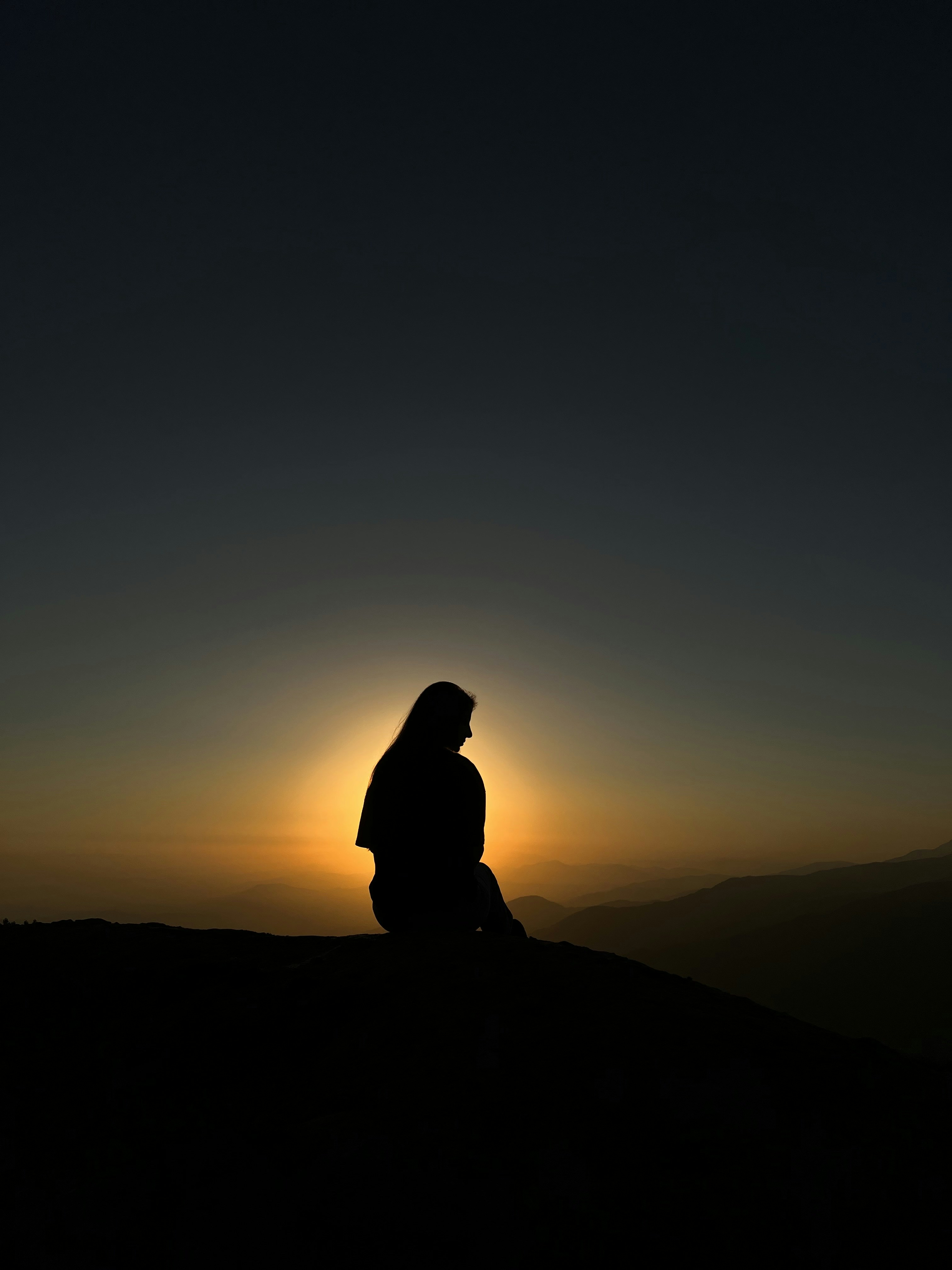 a person sitting on top of a hill at sunset