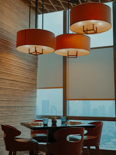 A sleek, handcrafted solid teak dining table set in a sunlit luxury apartment overlooking the Singapore skyline.