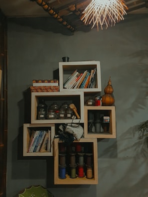 An artfully arranged shelf featuring textured throws, books, and small sculptural decor.