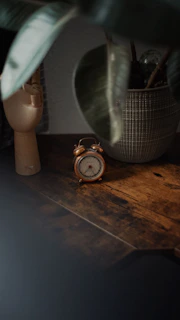 Vintage flip clock resting on a wooden side table surrounded by warm brown accents.