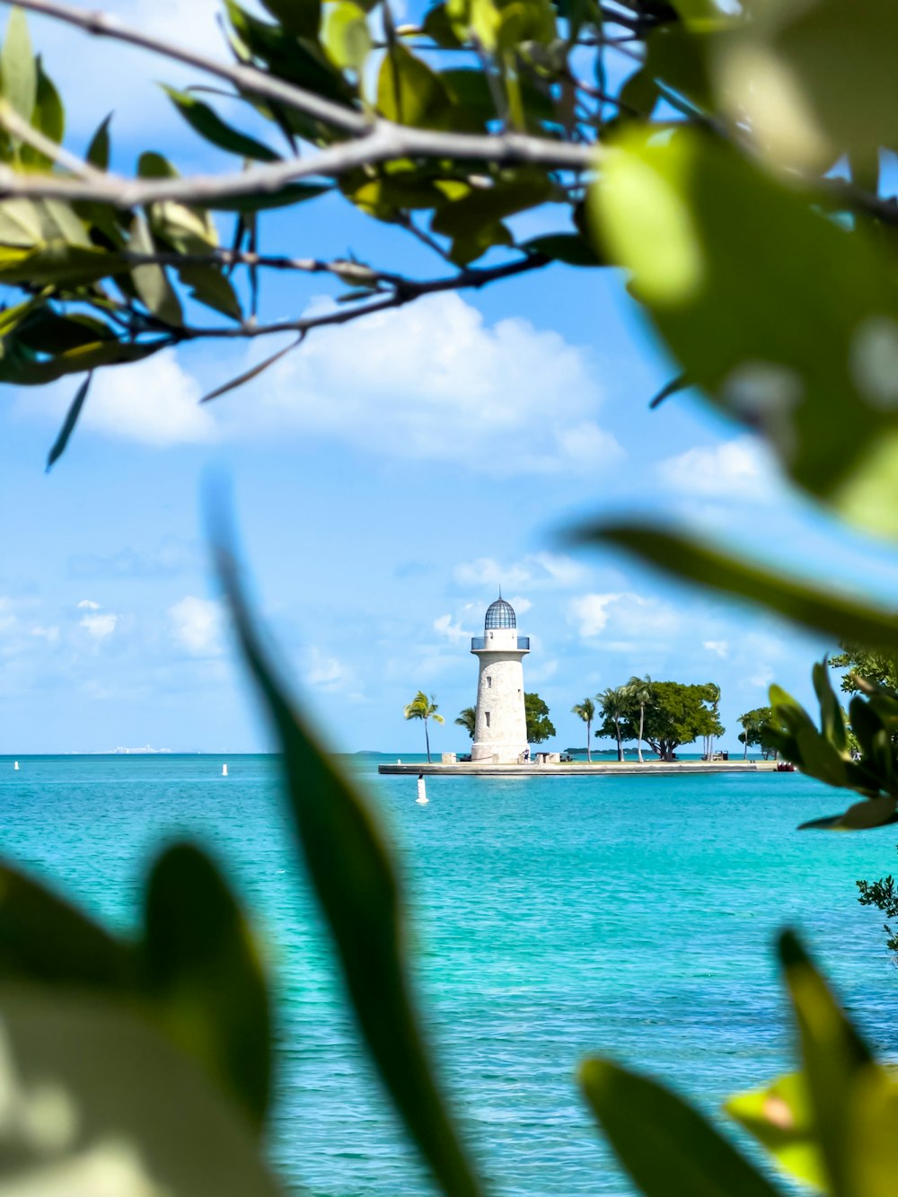 a white light house in the middle of the ocean