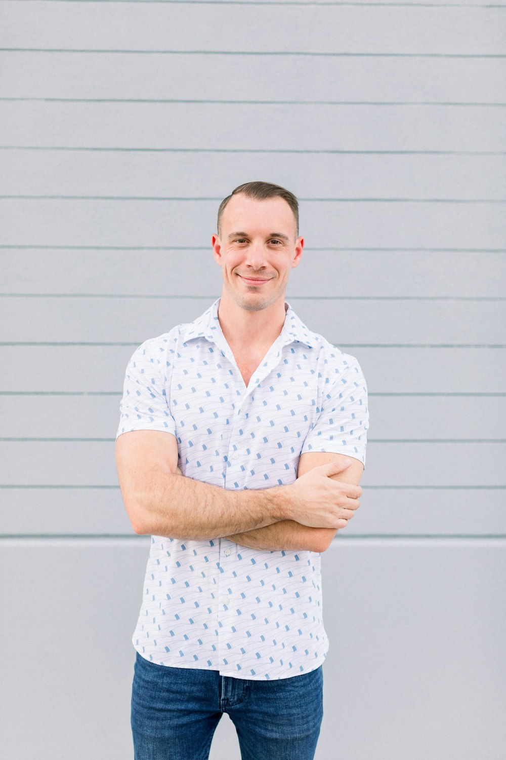 a man standing with his arms crossed in front of a wall