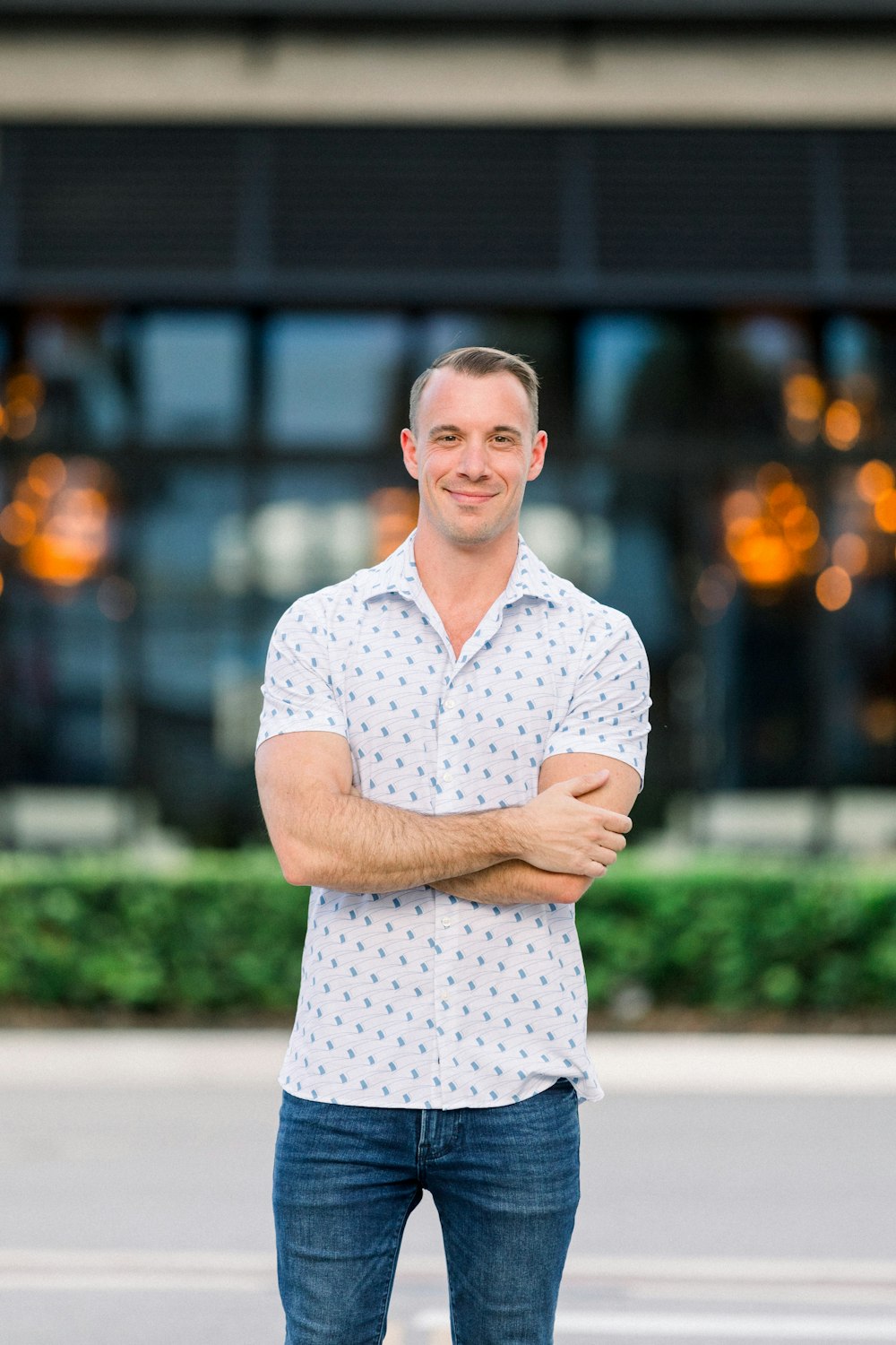 a man standing in front of a building with his arms crossed