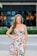 A happy woman wearing a trendy dress, smiling confidently in a bright urban setting.