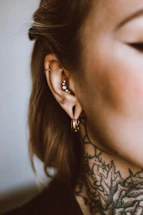 a woman with a tattoo on her neck and behind her ear