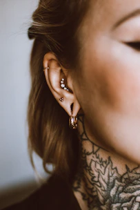 a woman with a tattoo on her neck and behind her ear