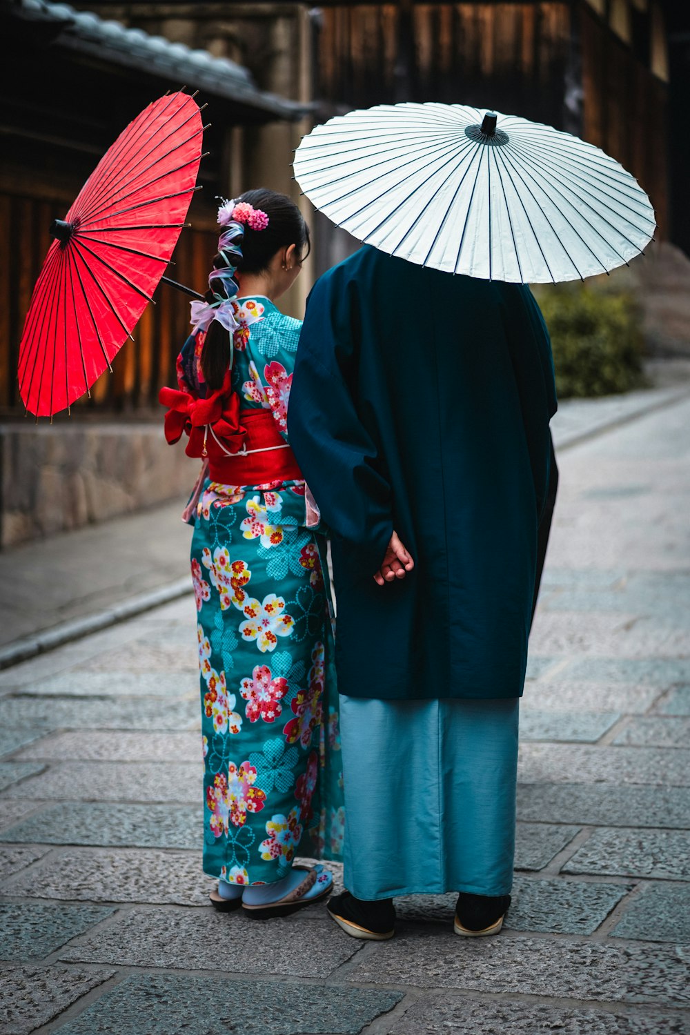 a couple of people standing next to each other holding umbrellas