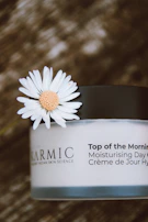 a jar of cream with a flower on top of it