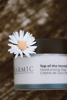 a jar of cream with a flower on top of it