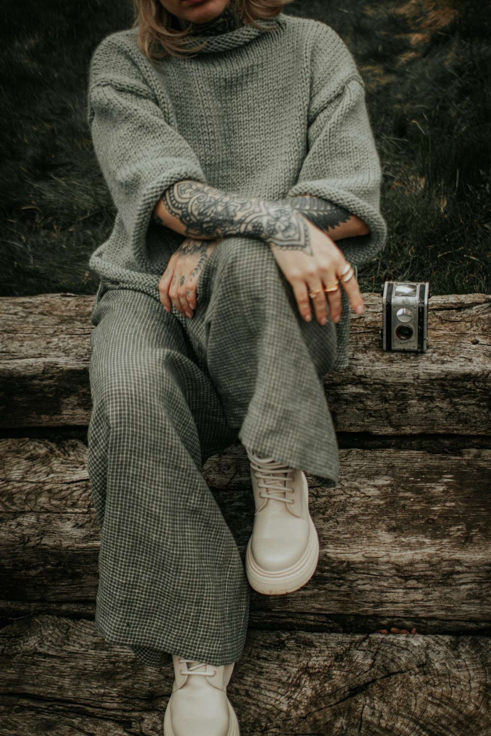 a woman with tattoos sitting on a log