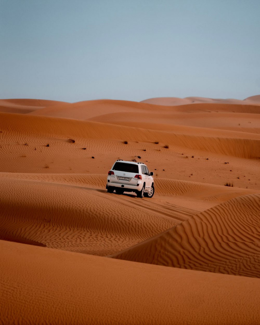 a van driving through the desert with sand dunes in the background