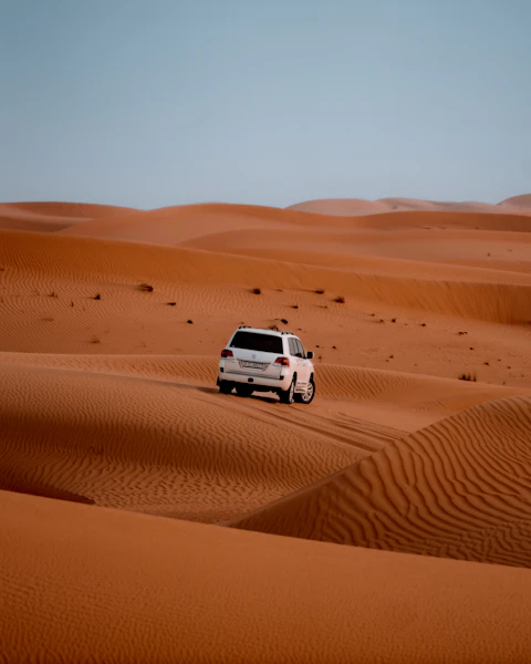 A white safari vehicle among Dubai dunes, shown in a mobile website concept