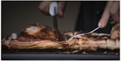 Close-up of a butcher slicing a fresh steak with a sharp knife.