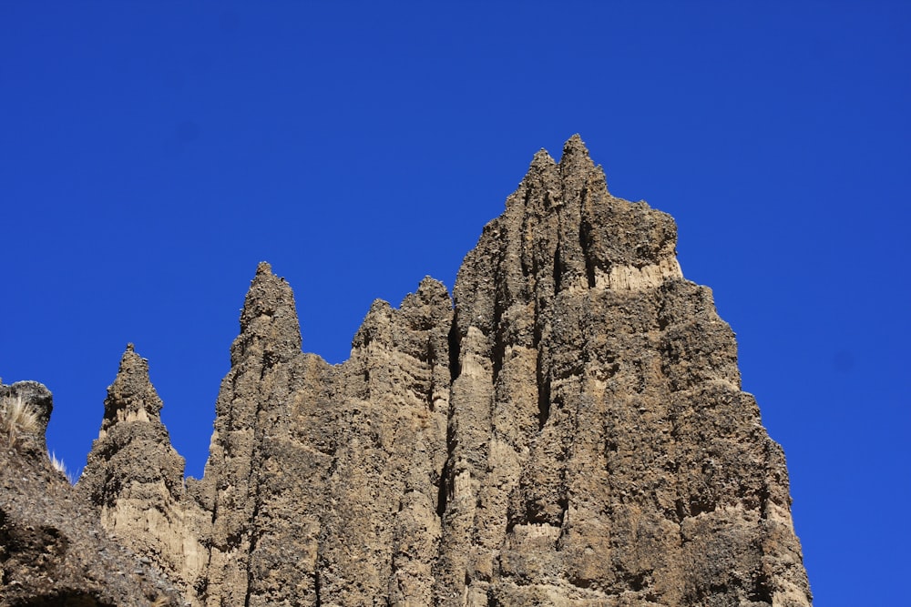a very tall rock formation with a blue sky in the background