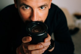 Close-up of a camera lens focusing on a model posing confidently.