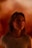 A person with long hair is gazing upwards with a contemplative expression. The background is a warm, blurred blend of orange and red tones, creating a serene and intimate atmosphere.