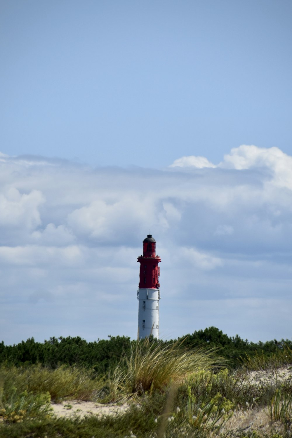 a red and white lighthouse sitting on top of a sandy beach