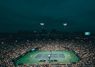 A lively tennis match in progress with players focused on the ball under bright outdoor lights.