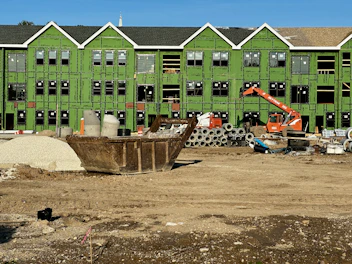 a construction site with construction equipment and a green building