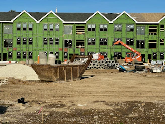 a construction site with construction equipment and a green building