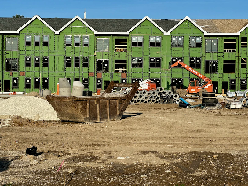 a construction site with construction equipment and a green building