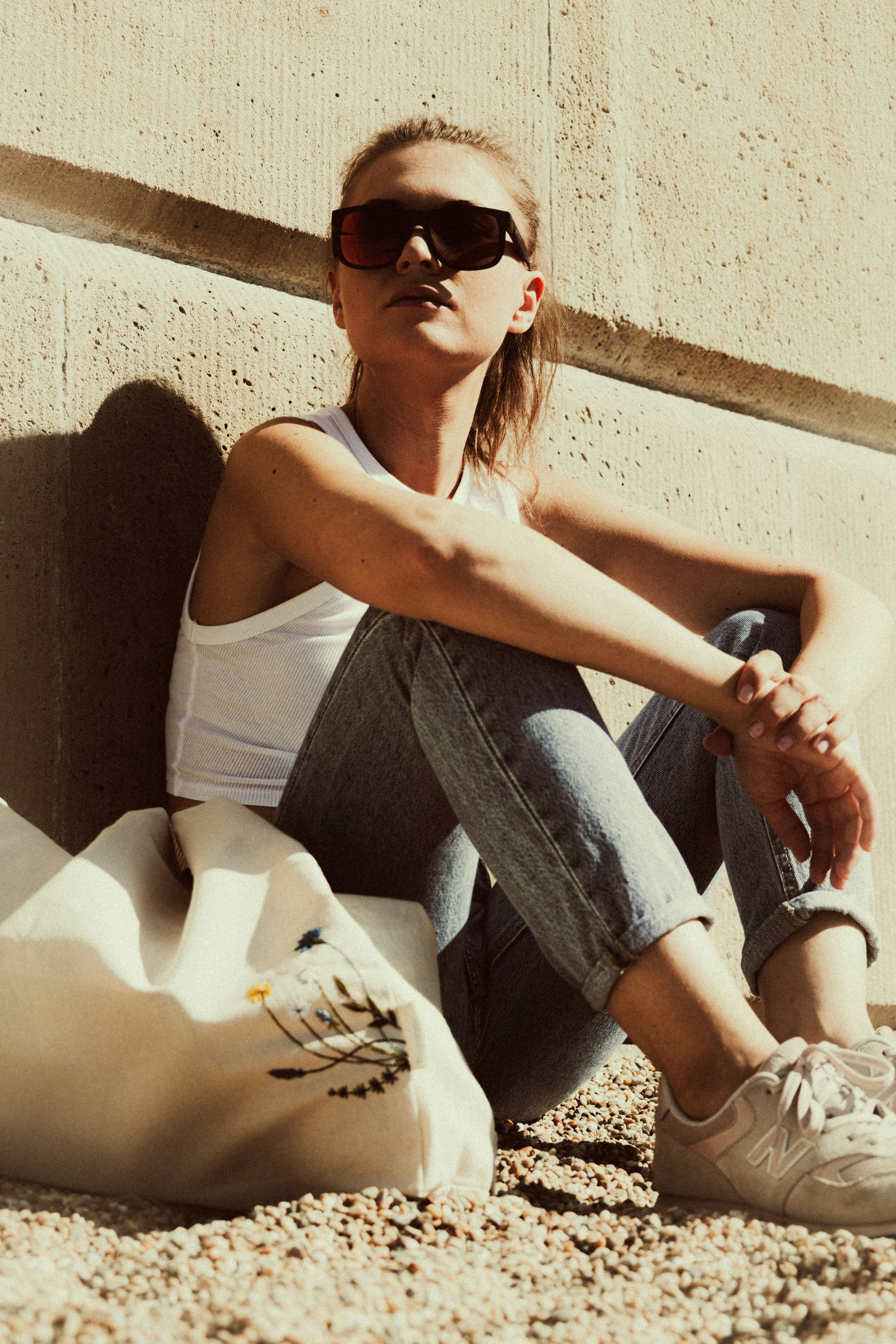 a woman sitting on the ground next to a cement wall