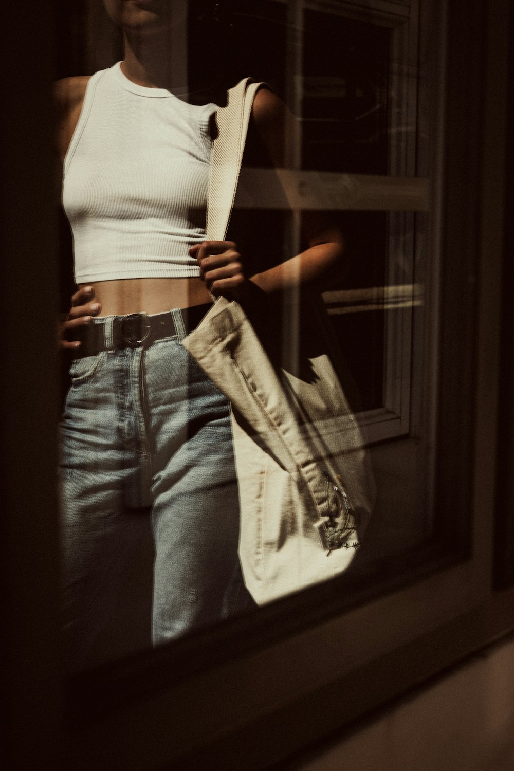 a woman standing in front of a window holding a purse