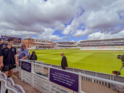 A vibrant cricket ground with players warming up under clear skies.