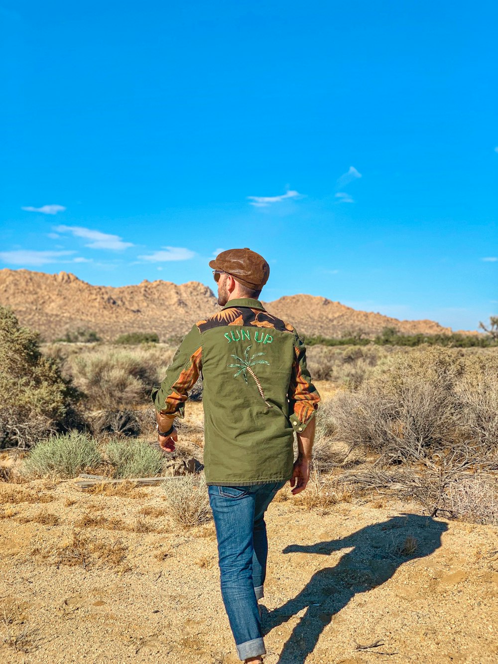 a man walking in the desert with a hat on