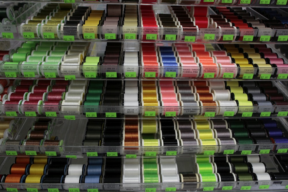 a display case filled with different colored spools of thread