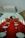 The interior of a vintage airplane features a long aisle lined with plush red seating on both sides. Each seat section includes white round tables in front of the seating areas. The design is reminiscent of mid-20th century luxury, with a spacious cabin and minimalist decor.
